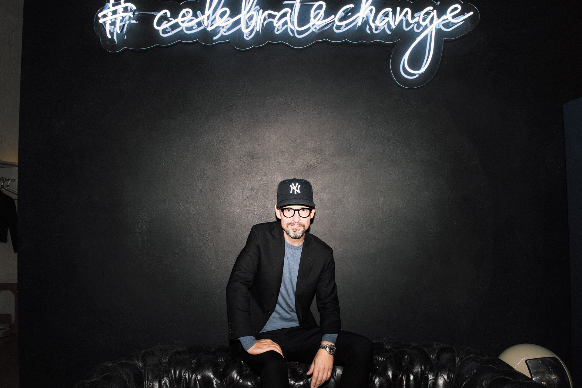Voigt zit op een bank in zijn kantoor met boven hem de festivalslogan “Celebrate Change”.